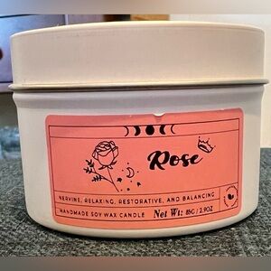 Small rose scented candle in a tin with a matching lid. NWOT.